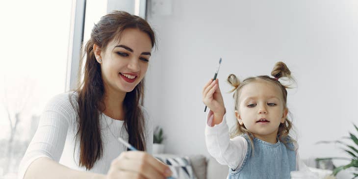 Toddler teacher shows a toddler student how to use watercolor