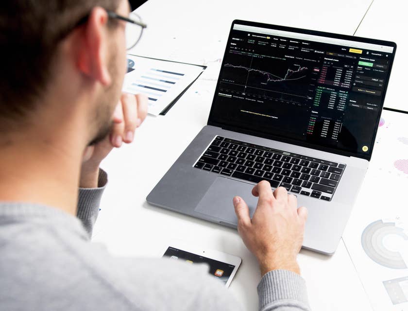 Trader wearing eyeglasses while looking at a real-time report on his laptop