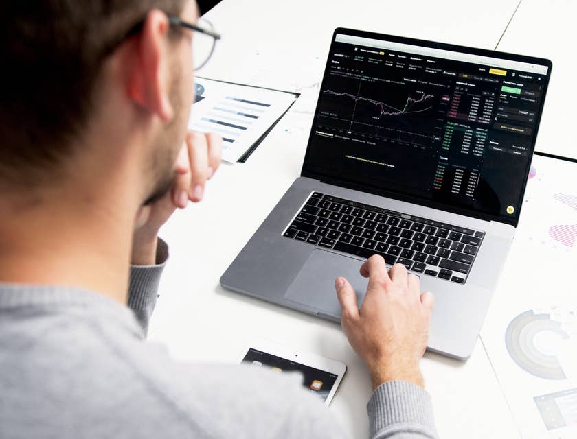 Trader wearing eyeglasses while looking at a real-time report on his laptop