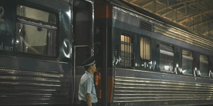 A train conductor waiting for the passengers to go onboard.