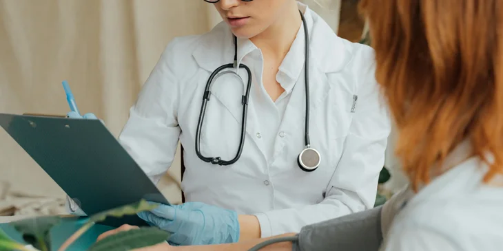 An urgent care nurse documents patient's information while performing a physical examination.