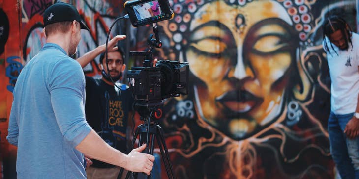 A videographer being directed by a video producer while shooting a music video scene.