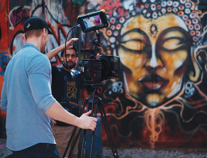 A videographer being directed by a video producer while shooting a music video scene.