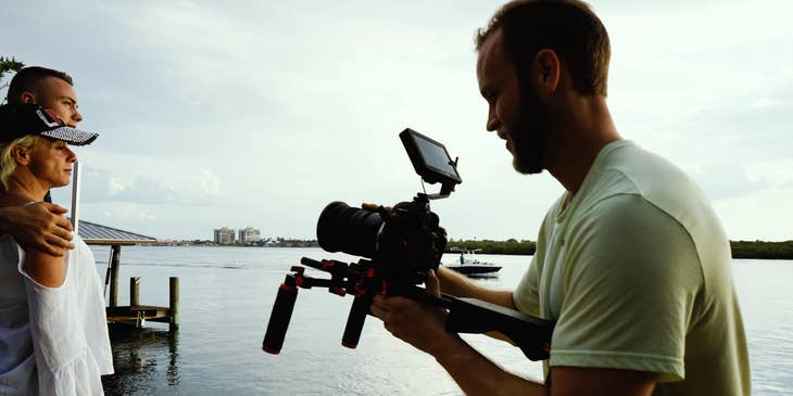 a couple on a lakeside being recorded by a videographer