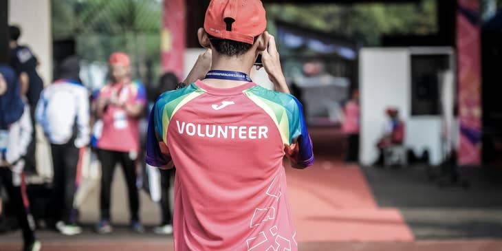 young Volunteer taking photos of the event and his teammates while standing