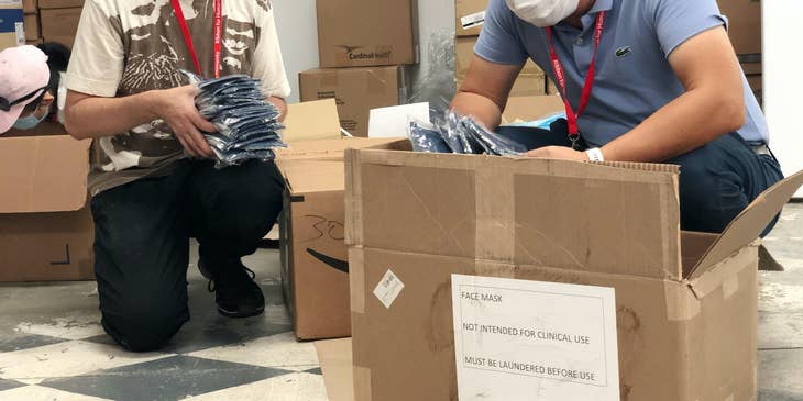 a crouching volunteer mentor showing the young man beside him how to check the items before packing