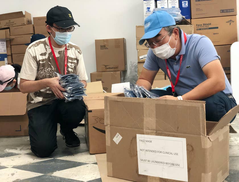 a crouching volunteer mentor showing the young man beside him how to check the items before packing