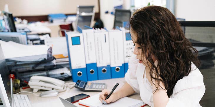 Warehouse operations assistant taking notes while checking the invoices