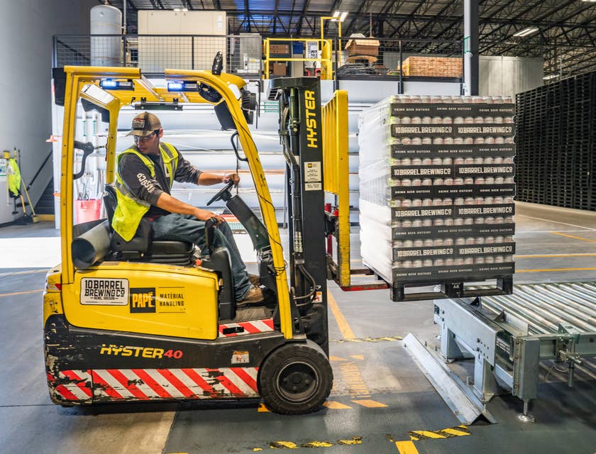 Warehouse worker stacking products using forklift