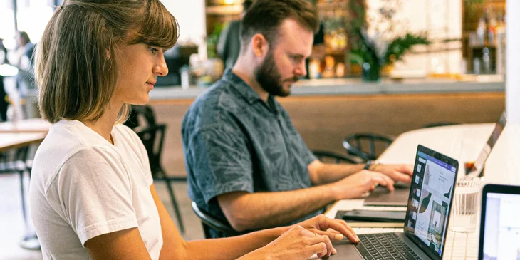 Two web designers typing on laptops at web design firm.