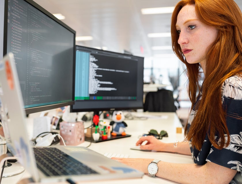 a web developer coding using her dual screen monitor and a MacBook