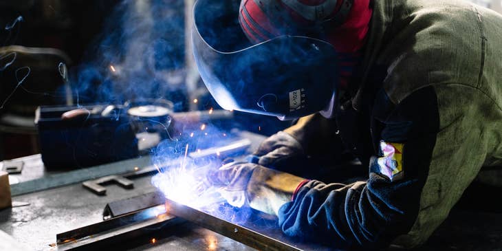 Welding engineer in full protective gear while working on a workshop