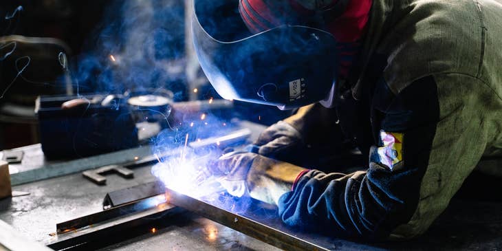 Welding engineer in full protective gear while working on a workshop