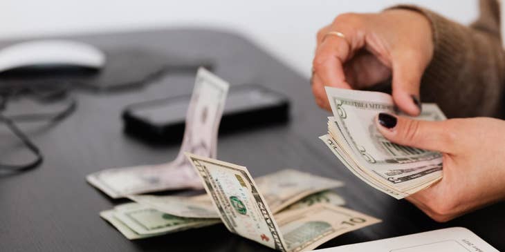 Person counting money at a desk.