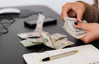 Pessoa contando dinheiro em uma mesa.