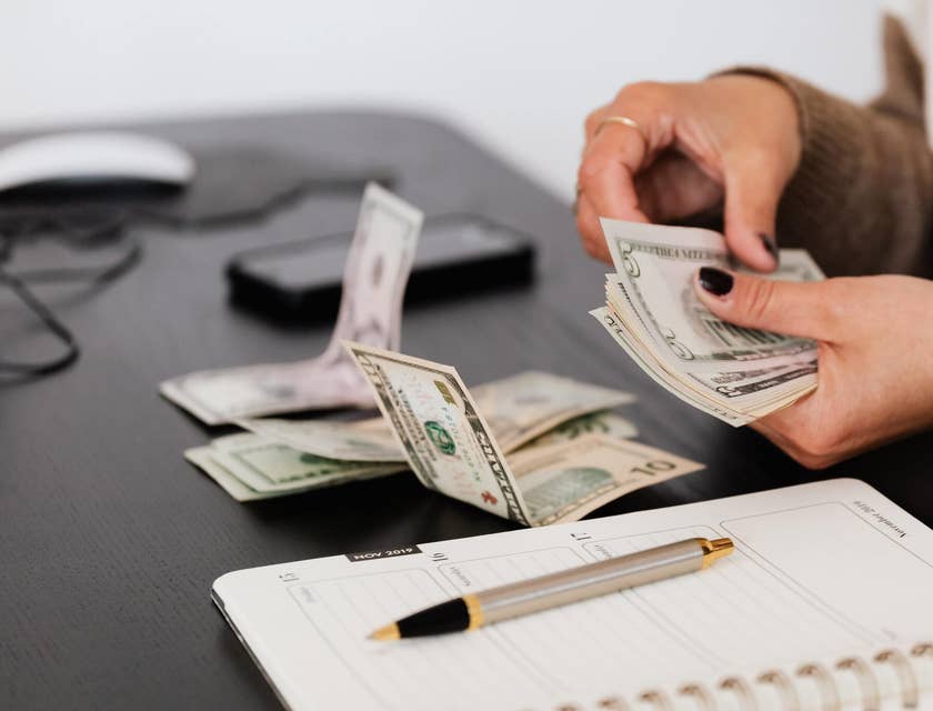 Person counting money at a desk.