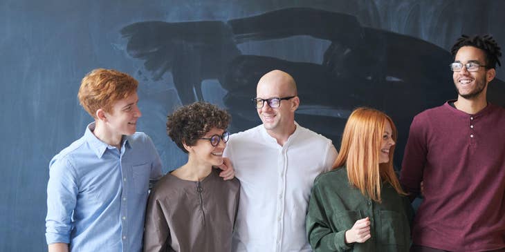 Group of people standing by a chalk board.