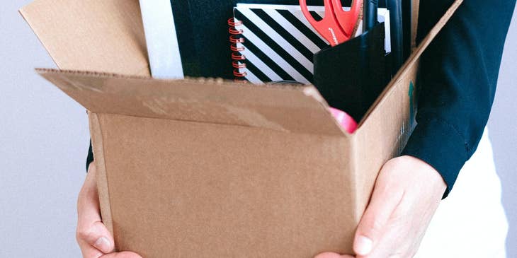 A woman carrying a box of office supplies.