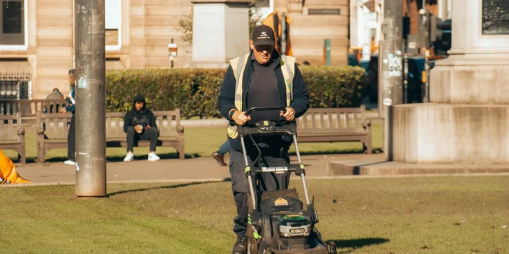 A yard worker mowing grass.