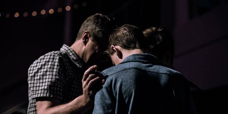 Youth pastor in solemn prayer with a young member of the community's church