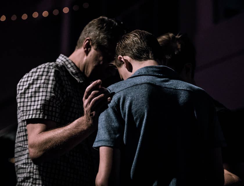 Youth pastor in solemn prayer with a young member of the community's church